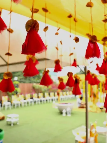 Delicate red tassels hanging from the yellow canopy of a Haldi mandap, showcasing the small details that make our decor special.