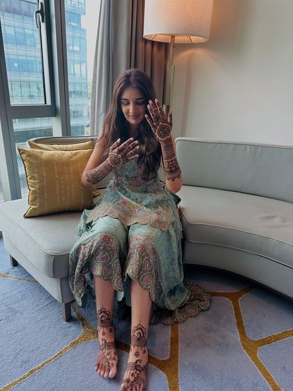 A lovely shot of the bride showing her complete mehndi. The patterns on her hands and feet are coordinated to create a unified and elegant bridal statement.