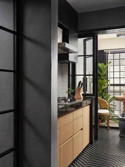 The kitchen in the Zen House opens up to the fountain area through a black-framed glass partition. The custom ash wood cabinetry and black chevron floor tiles create a graphic and modern culinary space.