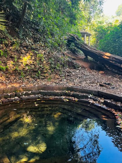 A beautiful, ancient stone well, with clear water reflecting the sky.