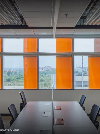 A meeting room at the Infosys campus benefits from the high-performance facade. The colored fins control glare and heat, creating a comfortable environment for collaboration while maintaining a visual connection to the outdoors.