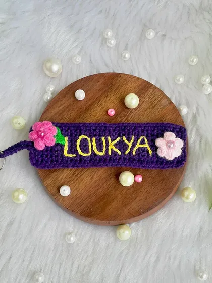 A personalized name keychain I made for a returning customer. The name is embroidered onto a crochet tag and decorated with little pink flowers.