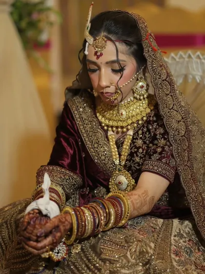 A candid shot of my beautiful bride in a traditional velvet lehenga. Her hair is styled in a classic bridal updo, adorned with intricate jewelry for a regal look.