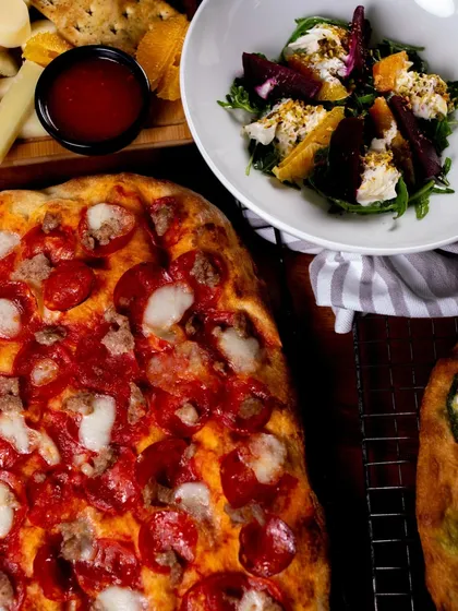 A catering spread featuring our pizzas, salads, and appetizers. We can create a custom menu for your event.