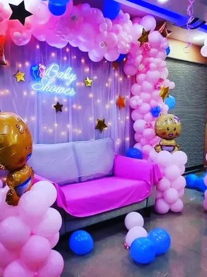 Here is a full baby shower decoration with a dedicated seating area. I used a mix of pink and blue balloons, a 'Baby Shower' neon sign, and character foil balloons to create a fun and celebratory atmosphere.