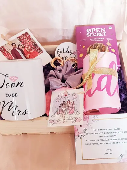 A simple yet heartfelt 'Soon to be Mrs.' hamper for the bride. It includes a custom mug, healthy snacks, and a personal note, all packed in a rustic wooden crate to send her love and good wishes.