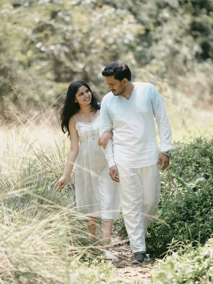 A couple walking hand-in-hand through a field, captured in a natural and candid style.