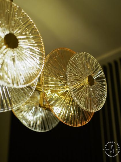 A linear chandelier featuring an arrangement of clear and amber-tinted textured glass discs. This fixture provides both direct and ambient light, adding a layer of sophistication and warmth to dining areas and boardrooms.