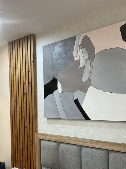 A 5ft x 4ft abstract painting installed above a headboard in a Bangalore bedroom. The soft grey, pink, and black palette creates a restful yet modern atmosphere.