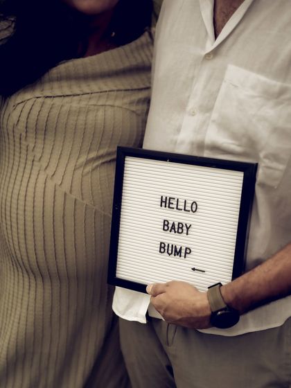 A close up shot focusing on the "Hello Baby Bump" sign, held next to the bump itself. This minimalist photo is a clean and stylish way to announce and celebrate the pregnancy.