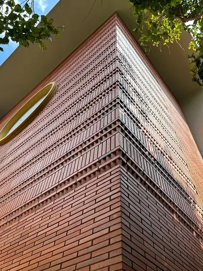 An upward view of the detailed brickwork on a building corner. We use intricate patterns and textures in our brick facades to create visual interest and celebrate the beauty of the material itself.