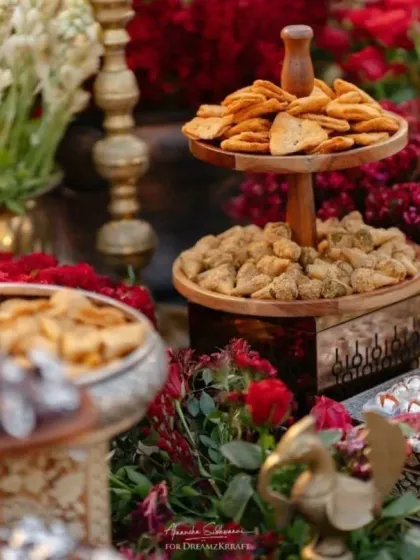 A close-up of the traditional Indian sweets and snacks served at a wedding event. The presentation is designed to be as beautiful as it is delicious.