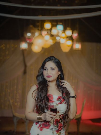 A glamorous evening look for a client enjoying a glass of wine. The makeup features a bold red lip and winged liner, perfect for a sophisticated party.