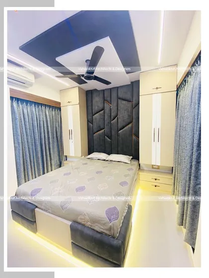 Another view of the master bedroom with the full-height headboard. The design also showcases the false ceiling with its contrasting colors and ambient lighting, which adds to the room's luxurious feel.