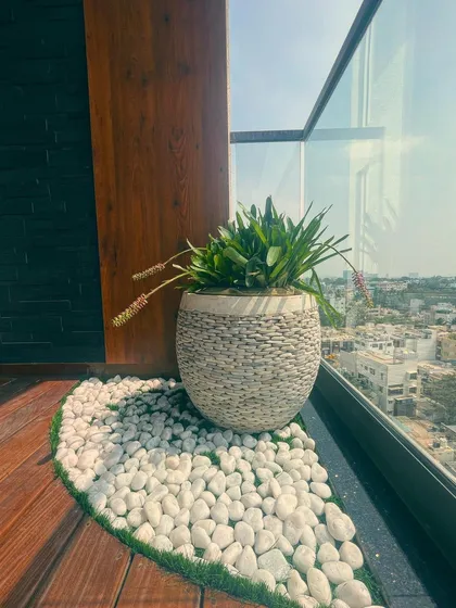 A wider shot showing how the pebble planter and white stones create a clean, curated corner on this beautiful wooden deck.