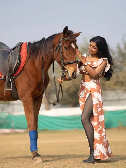 This shot captures the elegance of the model's pose as she interacts with the horse.
