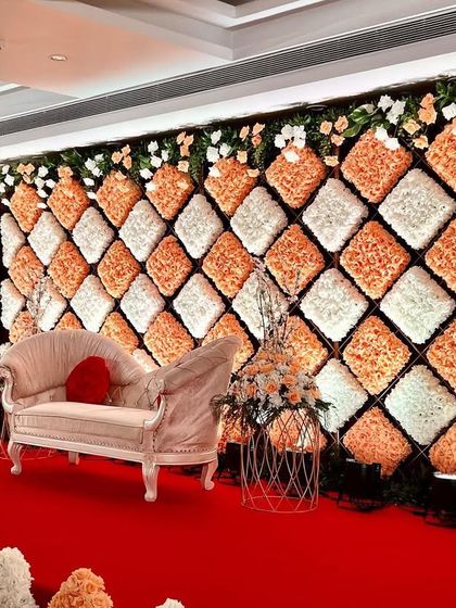 A unique and textural backdrop made of diamond-shaped cushions of orange and white flowers, creating a stunning visual effect on this reception stage.