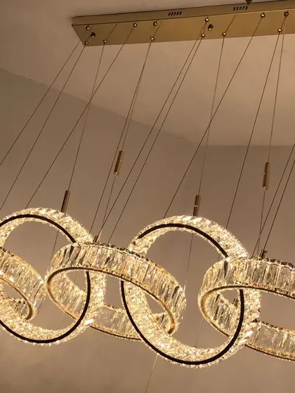 This luxury LED pendant features five interlocking rings of crystal. It's a glamorous and modern chandelier perfect for hanging over a long dining table, providing brilliant, sparkling light.