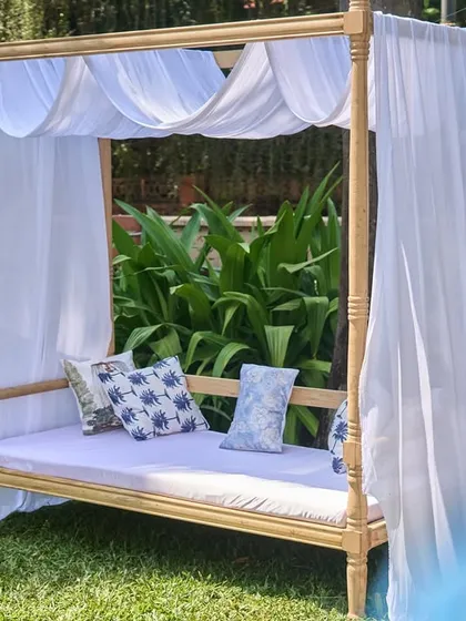 A cozy canopy daybed with white drapes and blue-patterned cushions, providing a comfortable and stylish spot for guests to relax.
