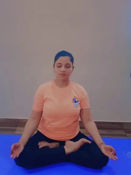 A practitioner sits in Ardha Padmasana for meditation, focusing on her breath to calm the mind. Regular meditation is a cornerstone of our teaching, helping to manage conditions like anxiety by cultivating inner peace.
