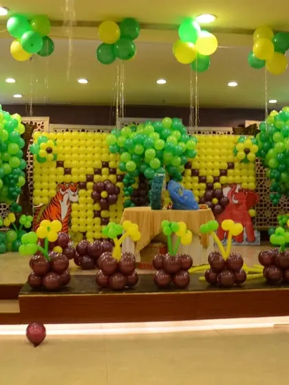 An elaborate jungle stage decoration made entirely of balloons. I created balloon trees, walls, and flowers in shades of green and yellow to build a complete jungle scene for the party.