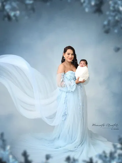 Like a dream, this mother holds her newborn, her flowing blue gown creating a sense of ethereal beauty. This portrait focuses on the elegance and grace of new motherhood, creating a truly timeless piece of art.