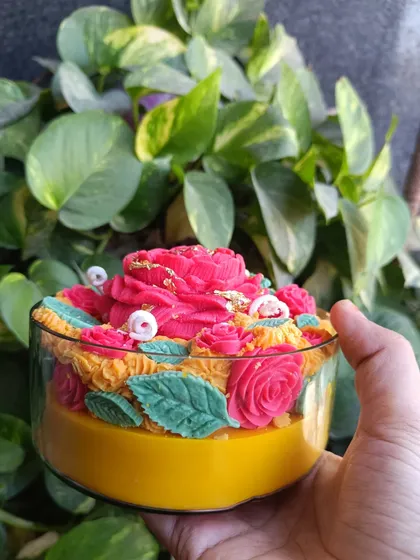 A hand-held view of the rose garden jar candle against a natural background.
