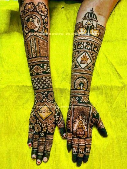 A beautiful design featuring the wedding date '15-5-23' prominently. The arms are decorated with peacocks, lotuses, and a traditional kalash.