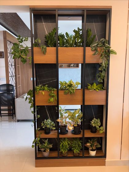Plants can be beautiful and functional. For this home, I designed a custom metal and wood partition that acts as a living divider. It separates the space while keeping it open and airy, filled with a variety of easy-care indoor plants that clean the air.