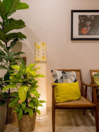 A close-up on the details: a handcrafted floor lamp, a rattan chair, and lush indoor plants that add a layer of tropical warmth.