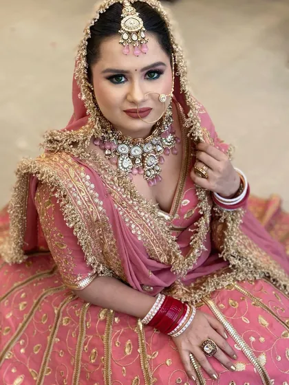 A full-length view of the bride seated, showcasing the beautiful flare of her lehenga and the graceful way she carries the entire look. She looks like true royalty.