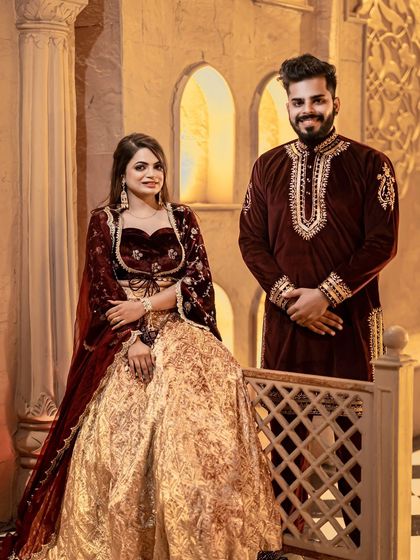 A classic and elegant portrait of the couple. The warm lighting and architectural details of the set provide a sophisticated backdrop for their beautiful traditional attire.