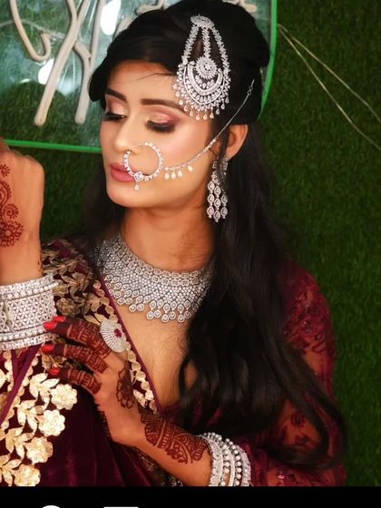 A model in a maroon velvet outfit with a full American Diamond set, including a necklace, passa, and nath. This is a glamorous look for a Muslim bride or a reception.
