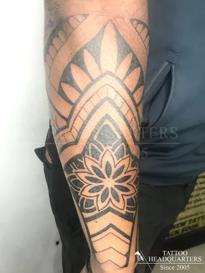A half-sleeve tattoo featuring a large mandala and other geometric patterns, creating a cohesive and intricate design.