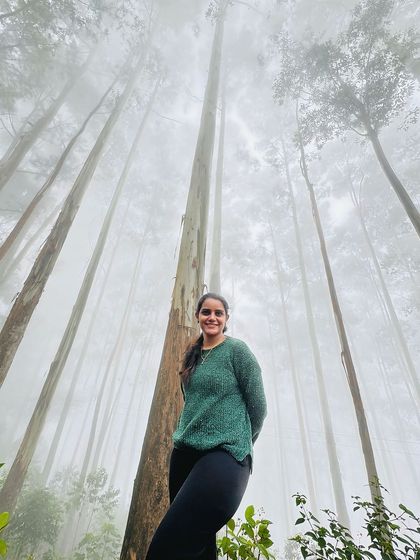 A trekker posing against the tall, misty trees of the Kodaikanal pine forest.