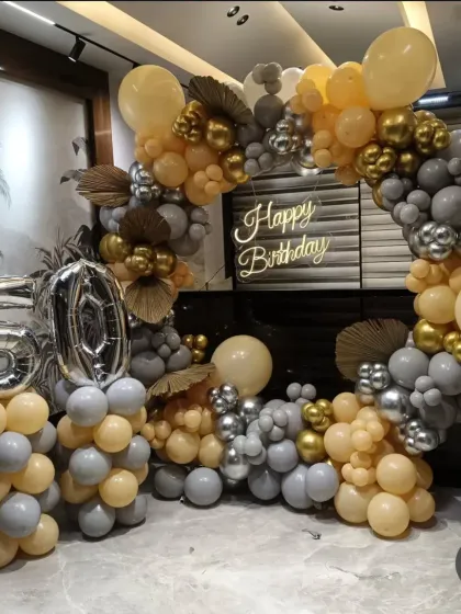 A 50th birthday party with a circular balloon arch in grey, gold, and beige, complete with large foil numbers.