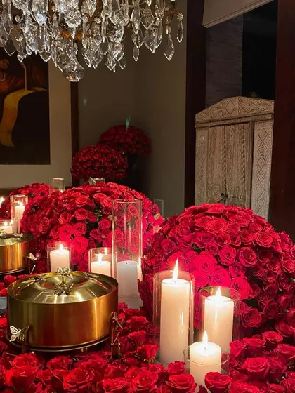 Another perspective of the rose-laden tablescape, showing the crystal chandelier above, which adds to the room's grandeur.