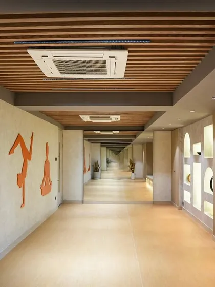 The corridor leading to the wellness areas at Trilogy, Ekta Tripolis. We used clean lines, a wood-slatted ceiling, and artistic silhouettes on the wall to create a calming and aesthetically pleasing transition space.