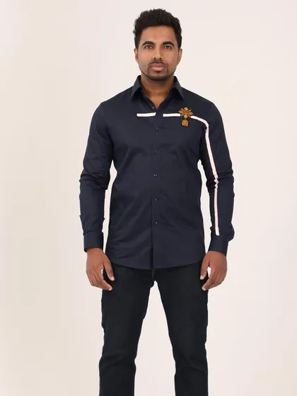This navy blue shirt is a study in refined detail, featuring a clean white stripe accent and a hand-embroidered golden crest. It’s a perfect choice for a polished, regal look that speaks of quiet confidence.