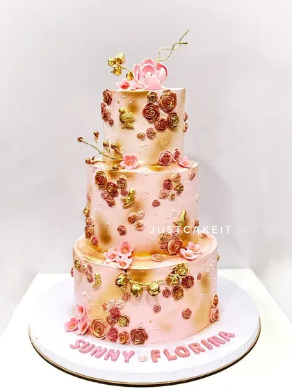 A tall and huge three-tier wedding cake in a beautiful rose gold and pink palette. This all-edible beauty was made with whipped cream and fondant accents.