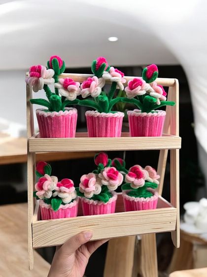 A whole shelf of our adorable pink potted flowers, ready for a craft fair. Each one is handmade and full of charm.