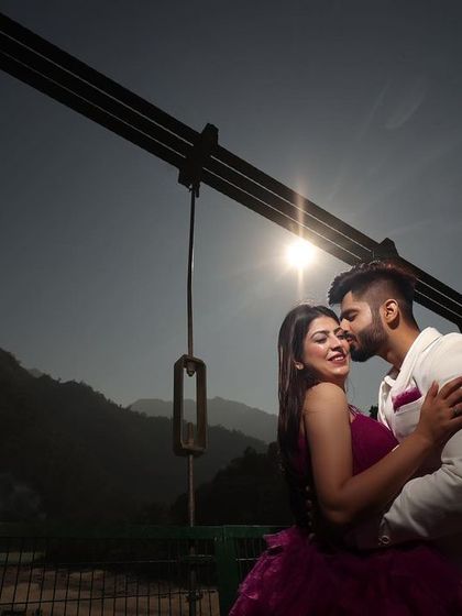 A beautiful silhouette shot against the setting sun on a bridge in Rishikesh. This technique creates a timeless and romantic image, focusing on the couple's embrace and the stunning natural scenery.