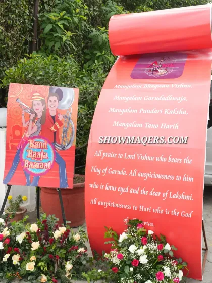 A creative 'Band Baaja Baaraat' welcome installation with a large scroll containing auspicious verses.