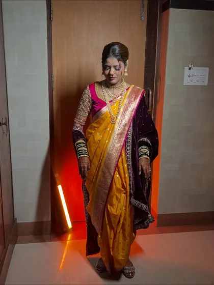 A full view of the elegant nauvari saree drape, paired with a velvet blouse and traditional green bangles.