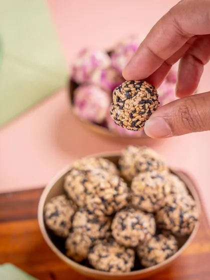 A close-up of a Til Laddoo, showcasing the texture of black and white sesame seeds. These laddoos are made the old-school way, with slow-roasted ingredients.