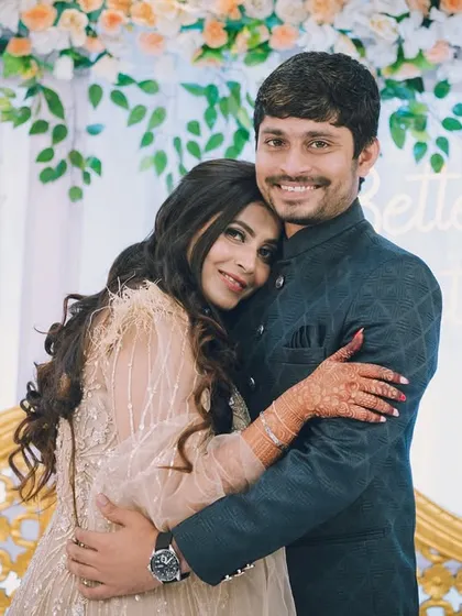A warm embrace from the couple, posing in front of a "Better Together" neon sign at their engagement party.