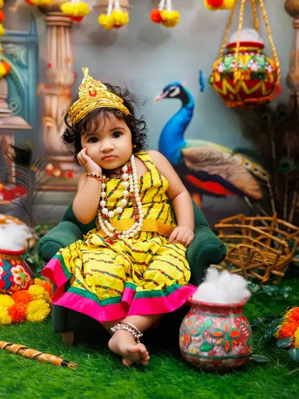 A thoughtful little Radha rests her head on her hand, looking absolutely adorable in her yellow dress.