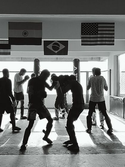 A black and white shot of our kickboxing class in session. The gym is filled with the energy of fighters training, sparring, and hitting the bags.