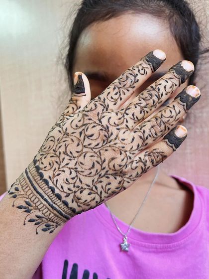 A full-coverage leafy vine design on a child's hand, showing that kids can also get intricate patterns.