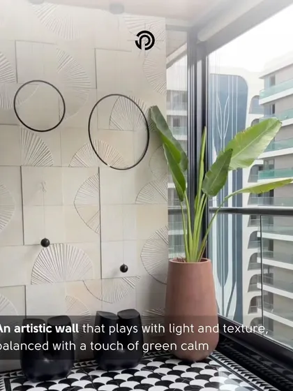 This artistic wall in The Aura House plays with light and texture. The geometric tiles are balanced by a tall plant, bringing a touch of green calm to the modern, graphic design.